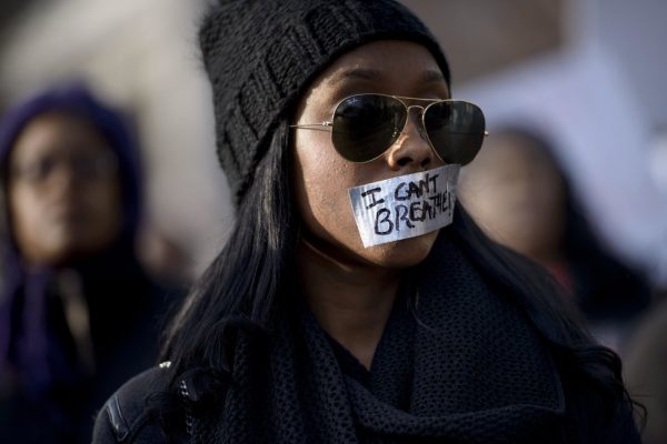 A woman listens to a rally with her mouth taped shut during the 